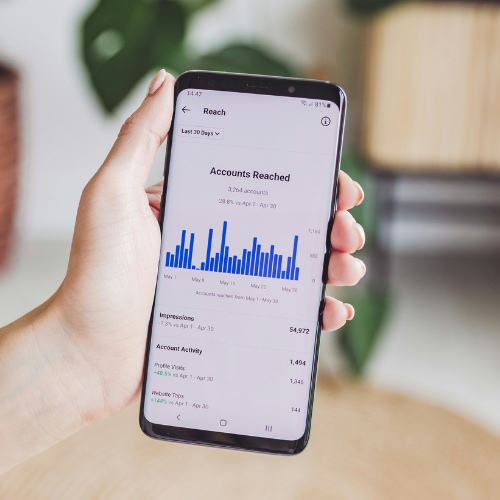Person holding phone displaying an graph for the accounts reached on social media