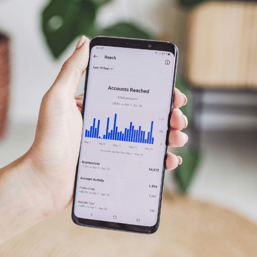 Person holding phone displaying an graph for the accounts reached on social media